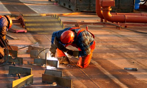 Shipyard welder during welding on the deck of the ship during the renovation